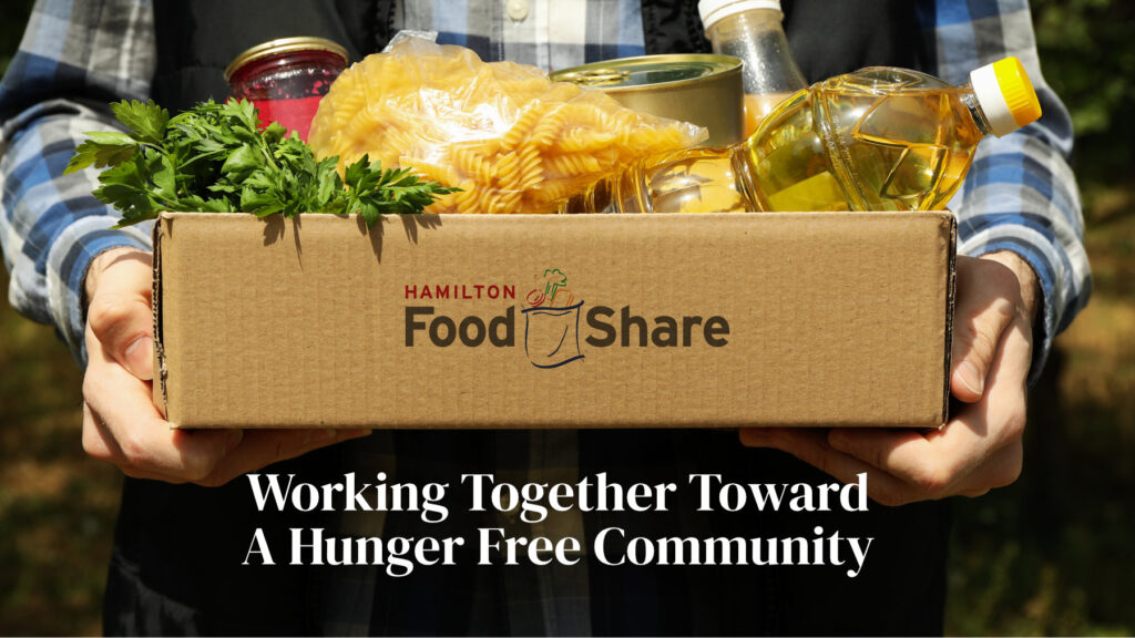 A person holding a Hamilton Food Share box of food. Working Together Toward A Hunger Free Community.